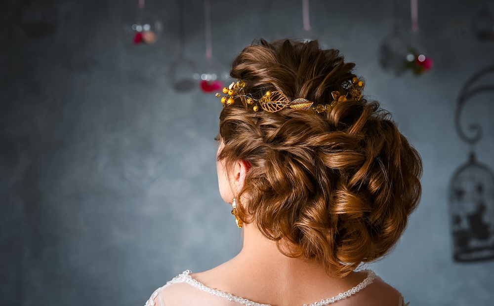 Duży kok ze złotą ozdobą we włosach jako przykład fryzury na wesele