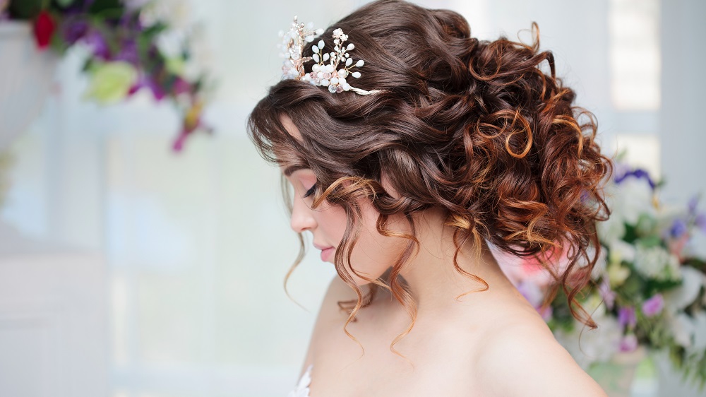Kręcone włosy spięte w duży kok jako przykład fryzury na wesele