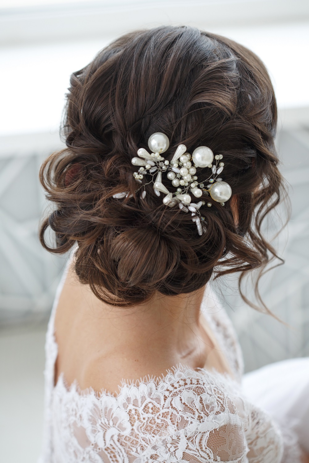 Delikatny, frywolny kok z luźno opadającymi pasmami kręconych włosów jako przykład fryzury na wesele
