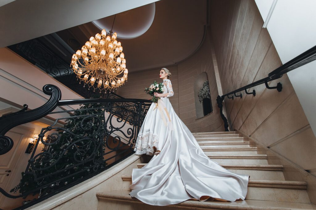suknia ślubna z trenem - panna młoda na schodach w pięknej sukni