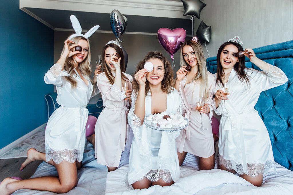 dekoracje na wieczór panieński - dziewczyny pozują do zdjęcia na łóżku podczas pijama party