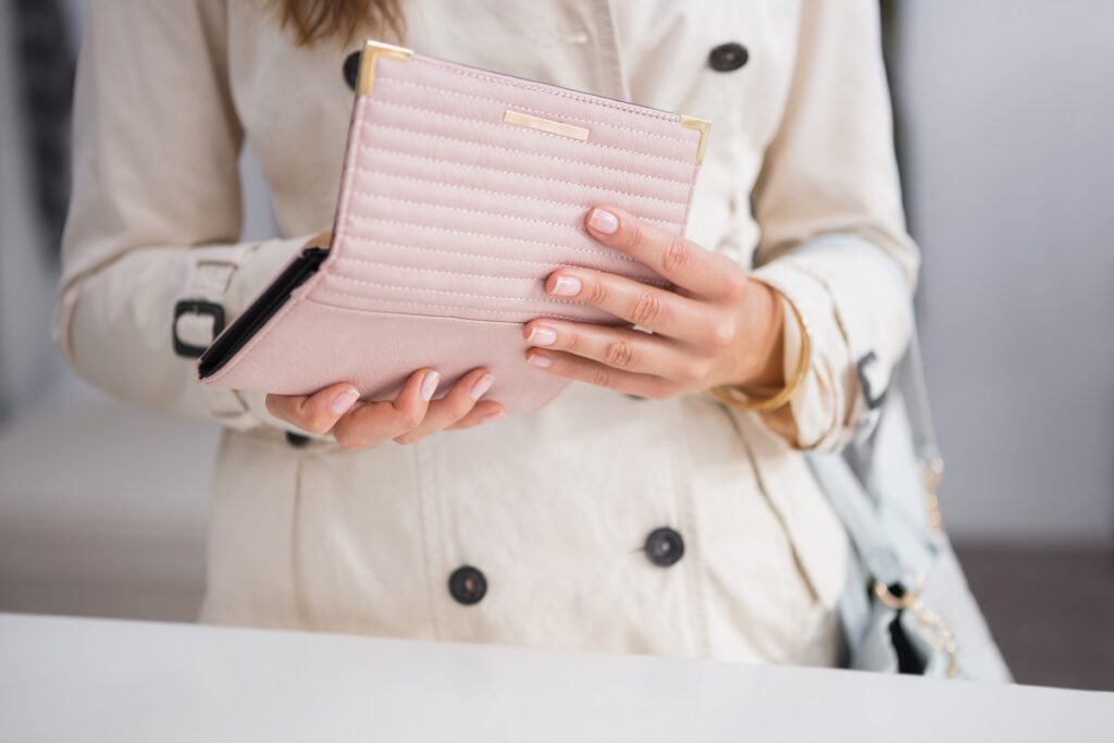 prezent na dzień matki-kobieta trzyma w rękach różowy portfel, który jest otwarty