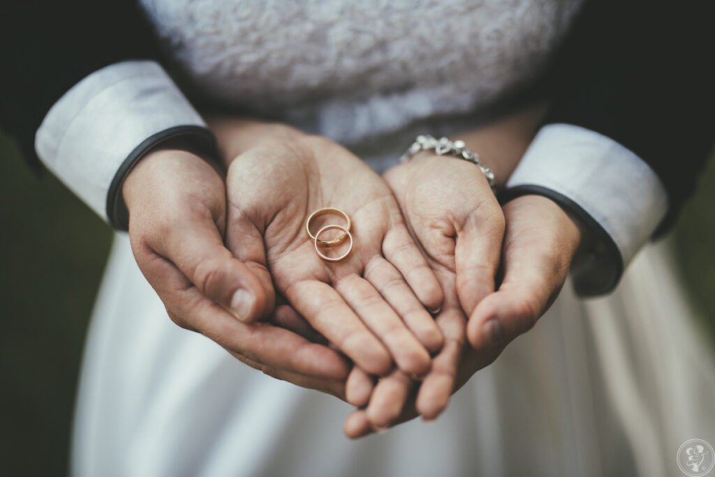 Przysięga małżeńska - nowożeńcy trzymający w ręku obrączki ślubne