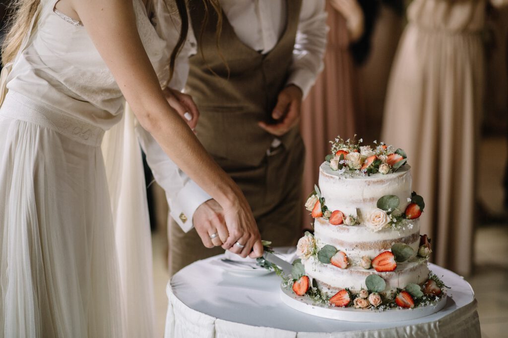 Atrakcje na wesele - para młoda krojąca tort weselny