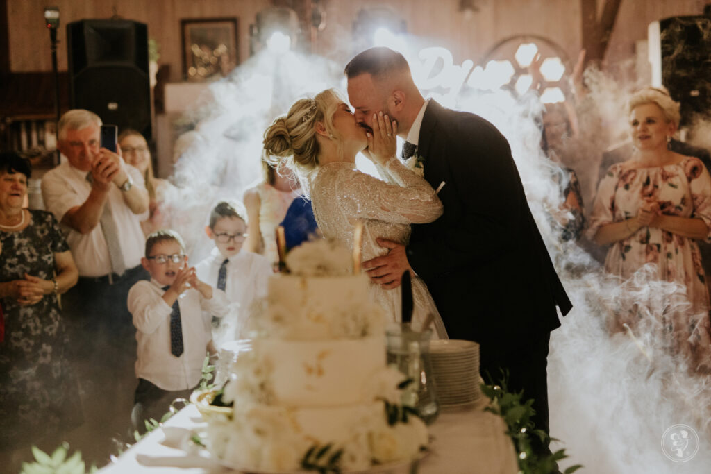Ile kosztuje sala weselna - para młoda całuje się przy torcie weslenym