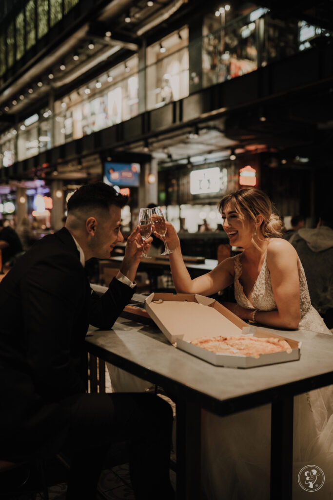 Para młoda jedząca pizzę na weselu 